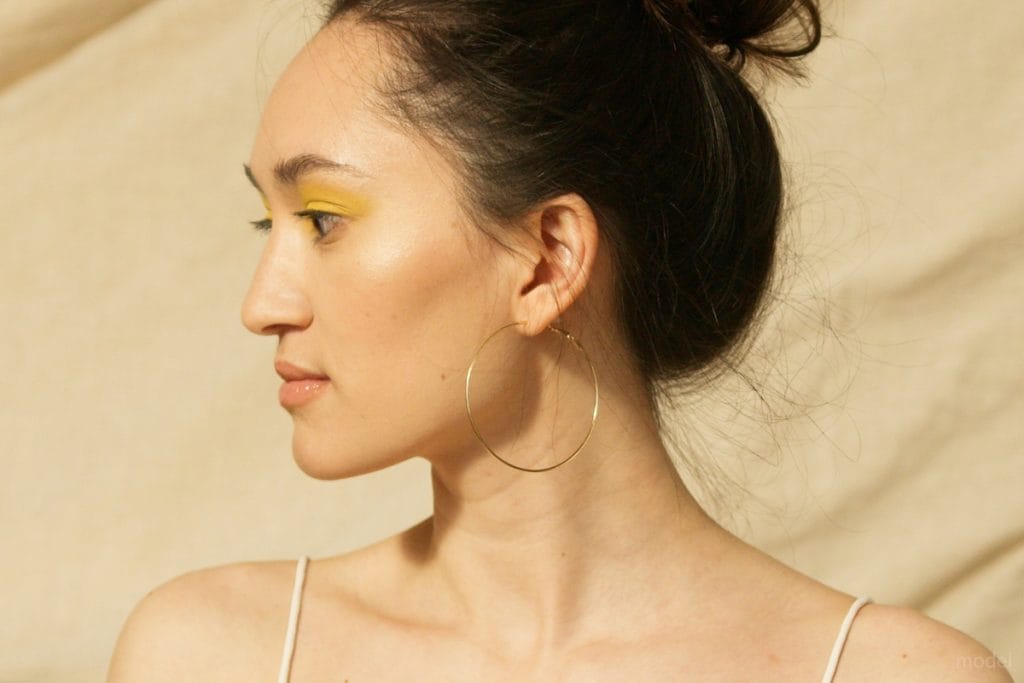 Side profile of a woman with her hair in a bun and a hoop earring in